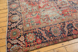 Distressed corner of antique Heriz carpet with stepped light blue spandrel and geometric navy border.