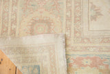 Vintage Sultanabad design rug corner, showing pastel floral pattern, fringe, and woven back.