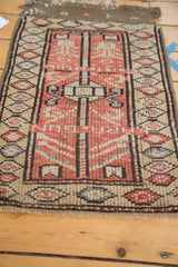 Close-up of vintage Oushak rug corner, showing repeating diamond cartouches and tattered fringe.