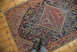 Distressed texture of a Mahal rug, with faded brick red medallion and indigo blue field.