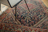 Distressed Mahal rug detail, showcasing intricate floral lattice in indigo blue, brick red, and blush.