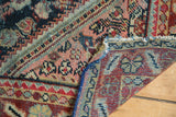 Close-up of hand-knotted distressed Mahal rug's fold, revealing brick red, indigo, and blush tones.