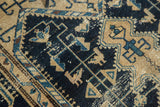 Rectilinear vinery and stylized animal motifs on a distressed navy and beige Malayer rug.