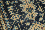 Distressed Malayer rug detail featuring stylized birds, geometric patterns in navy, beige, teal.