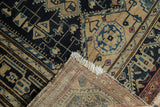Fringed corner of a distressed Persian Malayer rug, revealing its hand knotted foundation.