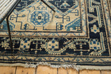 Distressed Malayer rug featuring aged fringe and border, with beige and navy geometric motifs.