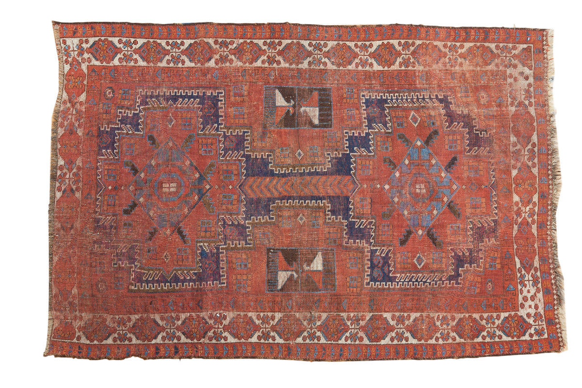 Distressed vintage Afshar rug featuring dual geometric medallions in madder red and navy.