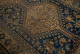 Distressed Qashqai rug detail: time-softened indigo field and copper geometric motifs.