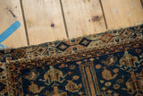 Tattered edge of distressed Qashqai rug with geometric border and indigo blue field.