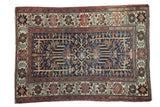 Distressed vintage Persian Baktiari rug with indigo field and geometric floral design, madder red accents.
