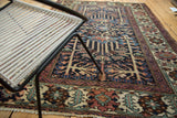 Distressed Baktiari rug detail, geometric border with madder red, indigo, and oxidized green patterns.