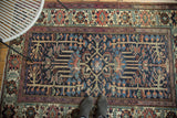 Distressed vintage Baktiari rug's intricate geometric field with indigo and madder red motifs.