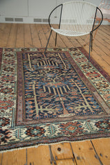 Distressed Baktiari rug's time-softened indigo, madder, and sea foam green floral corner.