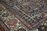 Distressed Baktiari rug with indigo floral field and ivory palmette border.