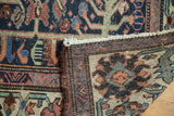 Hand-knotted vintage Baktiari rug corner: indigo, red, green floral pile and visible woven reverse.
