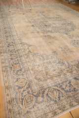 Distressed Sivas carpet corner, faded peach and teal floral patterns, exposed foundation.