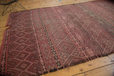 Tattered end of the vintage Jijim carpet featuring dusty rose and charcoal geometric lattice.