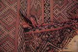 Frayed end, dusty rose and charcoal geometric patterns on a vintage Moroccan Jijim carpet.