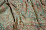 Draped distressed Sivas rug detail with muted sea foam, faded raspberry, and ivory angular motifs.