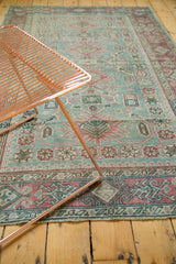 Distressed Sivas rug corner with faded raspberry, sea foam geometric patterns and fringe.