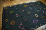 Moroccan Kilim rug with vivid embroidered diamond patterns on a jet black ground.