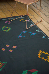 Jet black Moroccan Kilim field with embroidered diamond elements in aqua, green, yellow, fuchsia.