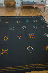 Jet black Moroccan Kilim with scattered geometric embroidery in aqua, green, yellow.