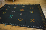 Geometric Moroccan Kilim rug with vibrant diamond embroidery on jet black, white zig-zag border.