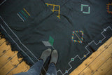 Black Moroccan Kilim with aqua, green, saffron geometric agricultural motifs and border.