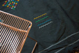 Moroccan Kilim rug's black field shows aqua, green, saffron flowing water and geometric diamond patterns.