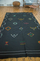 Black Kilim rug end with bright green, red, yellow wavy motifs and white border pinstripes.