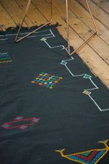 Jet black Moroccan Kilim carpet detail with a white stepped contour border and multicolored diamond motifs.