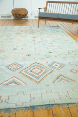 Moroccan Kilim carpet showing embroidered serrated diamonds, geometric motifs, and pale blue fringe.