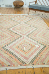 Visible patch fill-ins within geometric diamonds of a distressed vintage Jijim carpet.