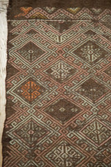 Hand-woven geometric diamond pattern on vintage Jijim rug in blush, tangerine, and silver.