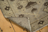 Vintage distressed Oushak rug corner, revealing its woven foundation, fringe, and textured pile.