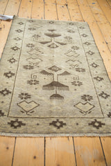 Fringe and distressed beige pile of a vintage Turkish Oushak rug with dark brown geometric motifs.