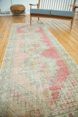 Distressed vintage Oushak runner showcasing abrashed pink, gold, and blue rococo patterns.