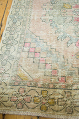 Textured blush field of a Distressed Oushak rug, showing dusty gold and seafoam blue rococo leaves.