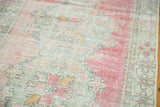 Distressed Oushak rug close-up: heavy abrashes reveal blush, grey patterns, and visible knot heads.
