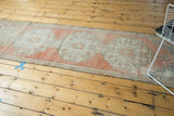 Distressed vintage Oushak runner with faded blush and ivory tones, revealing visible foundation.