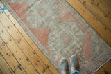 Distressed vintage Oushak runner displaying blush medallion, ivory field, and foundation wear.