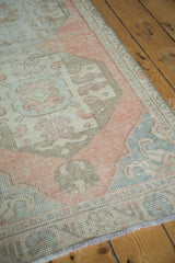 Distressed Oushak runner corner with worn blush, ivory, and sea foam blue pile.