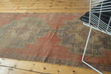 Distressed Oushak runner with scalloped medallion in cinnabar red, beige, and aubergine.
