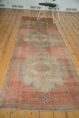 Distressed vintage Oushak runner corner, faded pale cinnabar red and beige geometric patterns.