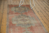Distressed Oushak runner's scalloped medallion with faded cinnabar red and pale mauve.