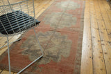 Distressed vintage Oushak runner showing muted red field with faded scalloped medallions.