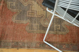 Close-up of distressed vintage Oushak runner pile, showing worn cinnabar red and aubergine patterns.