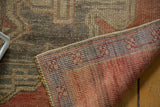 Vintage distressed Oushak runner edge, showing muted pile and vibrant foundation colors.