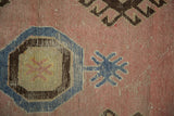 Distressed vintage rug detail: blush pink field, blue octagonal motif, and worn texture.